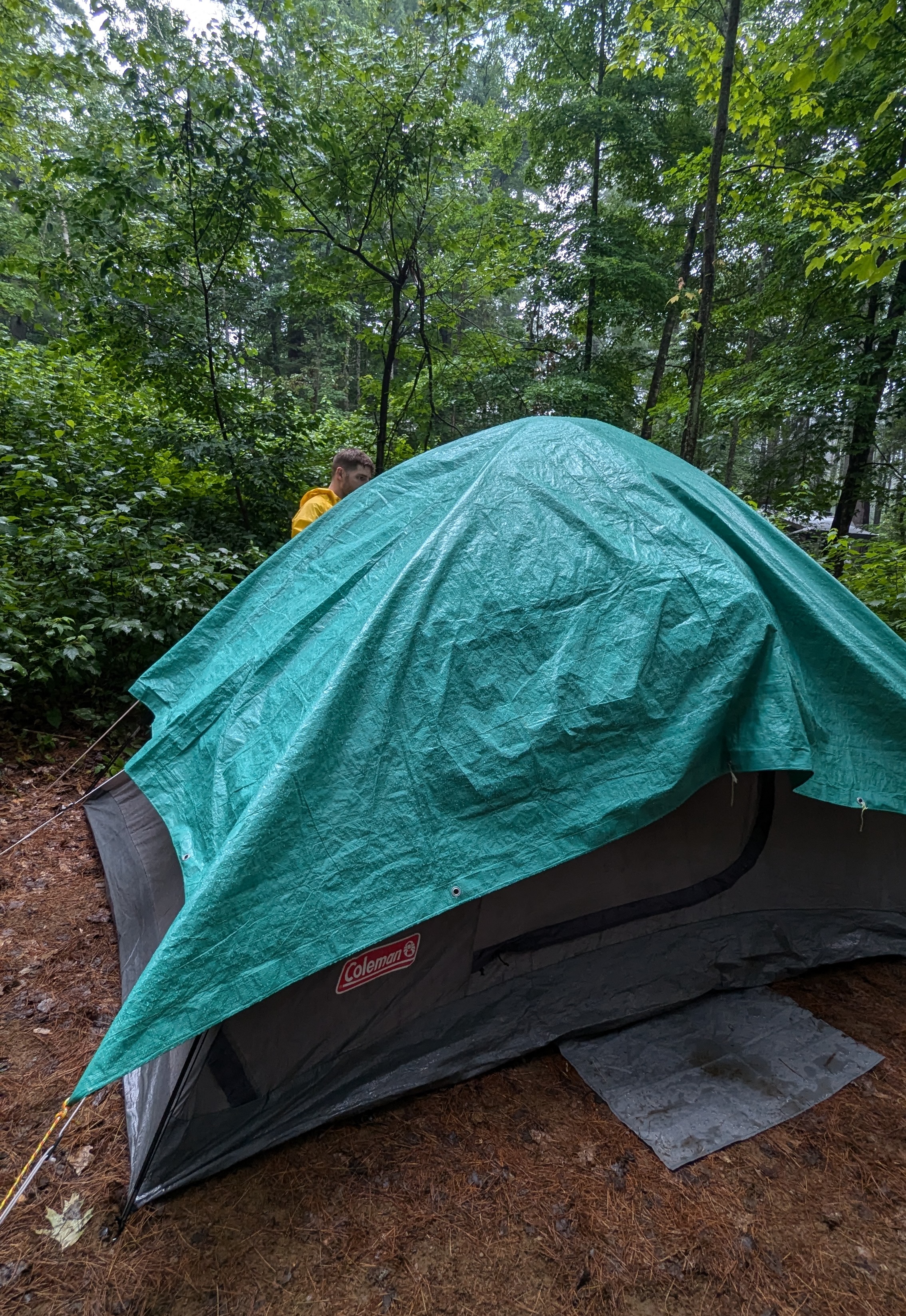 Phil walking behind a tent, tying down a tarp on top of the tent