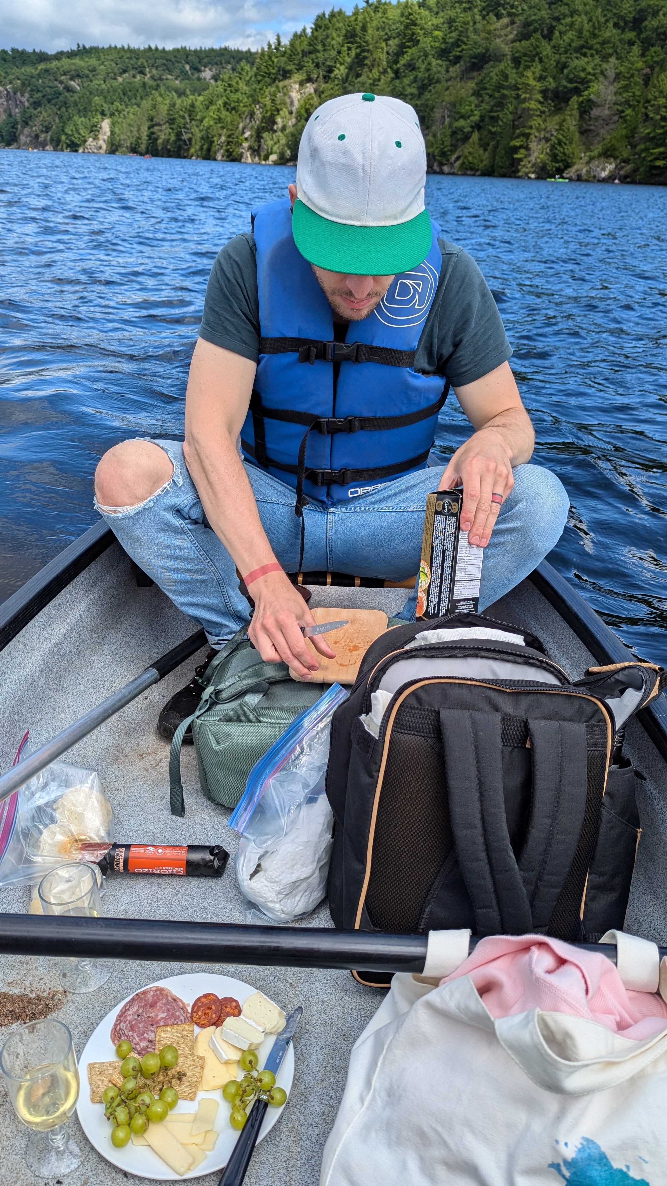 Phil sitting in a canoe, preparing dried meats and cheeses for a picnic on the lake