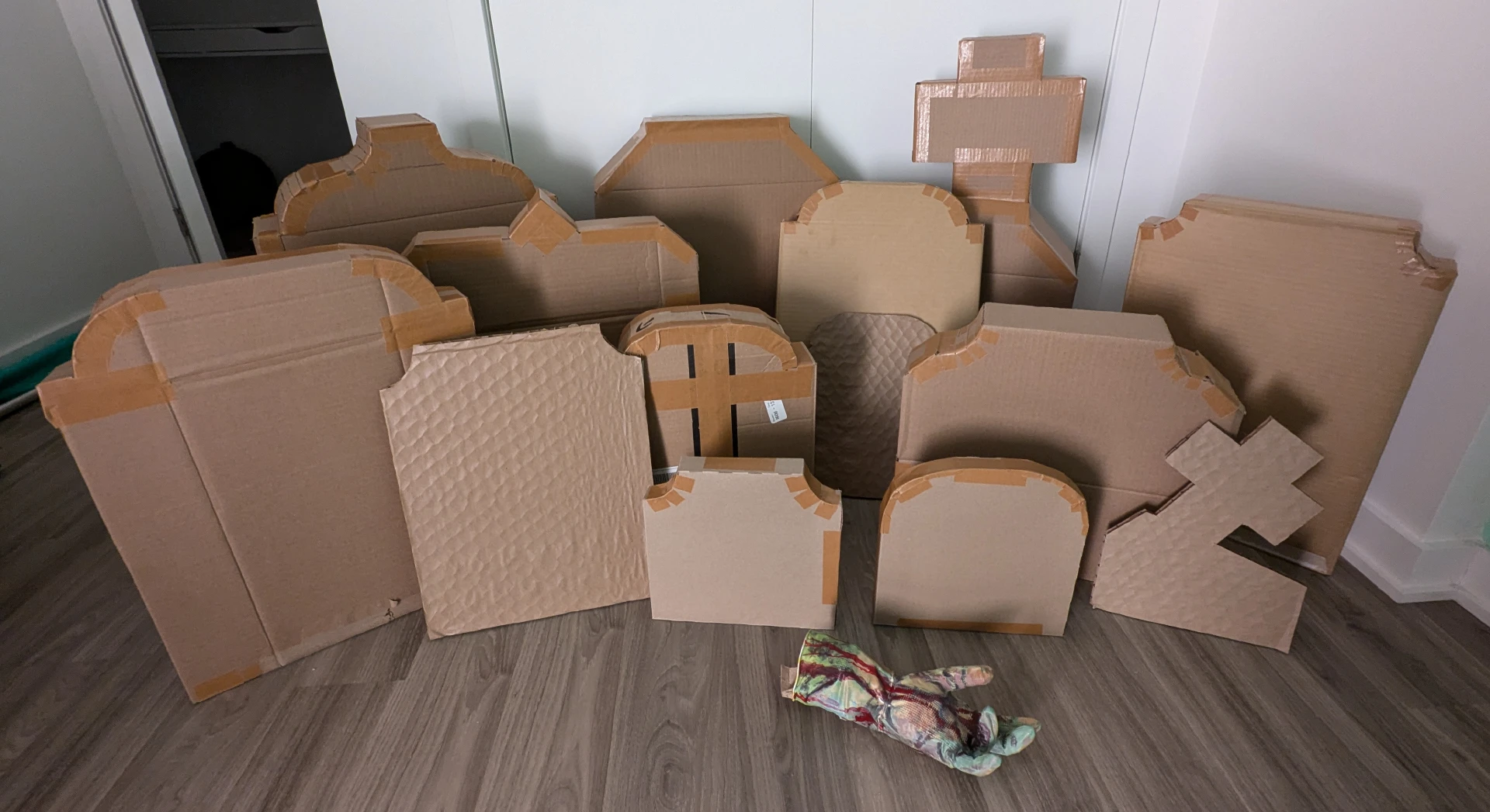 A set of 14 cardboard gravestones and a rubber glove zombie hand