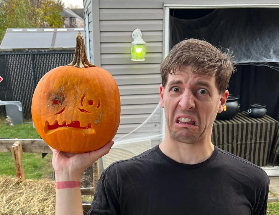 Phil holding a jack-o-lantern, making the same face