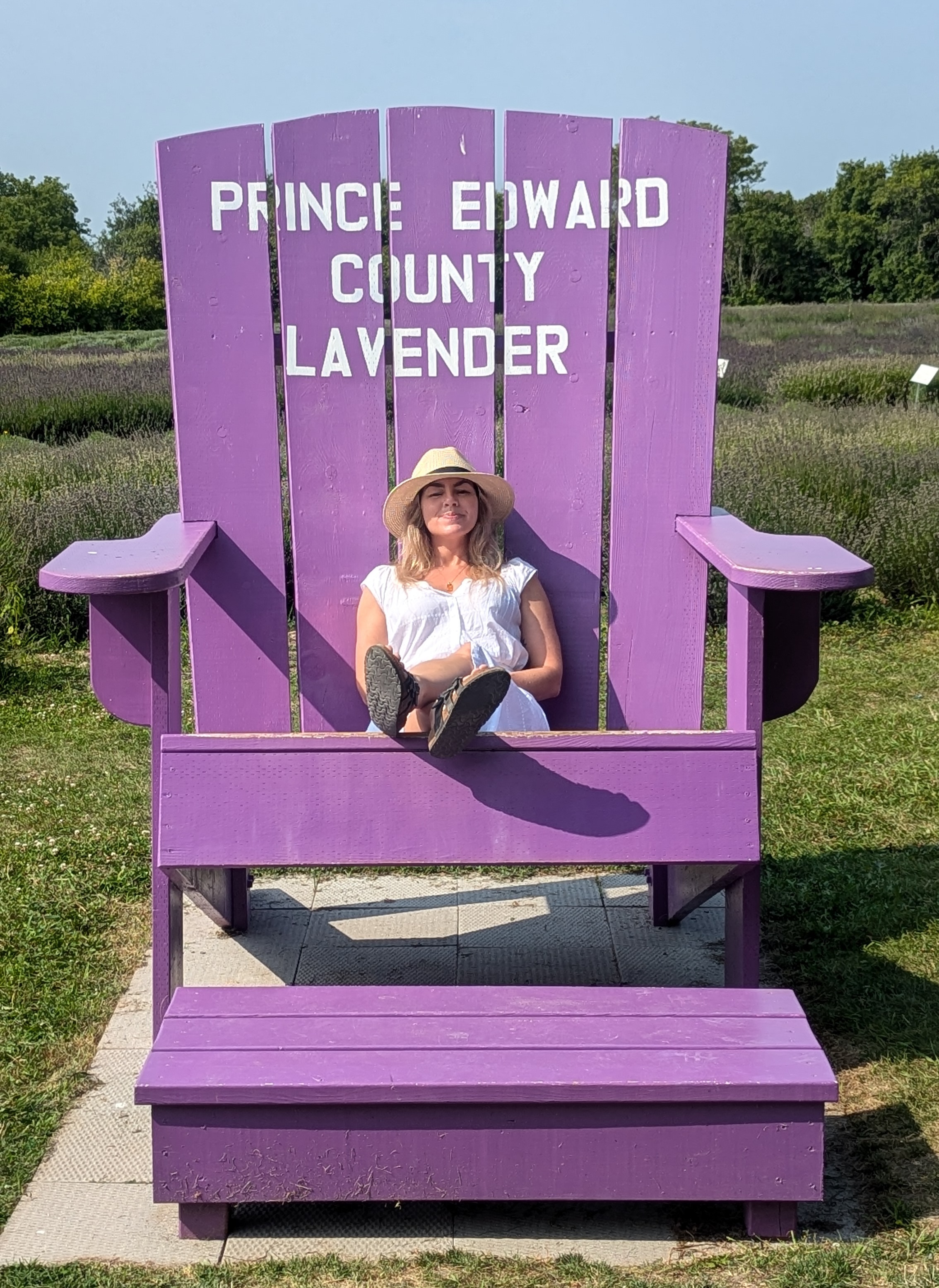 Laura sitting in a giant lavender-coloured Adirondack chair