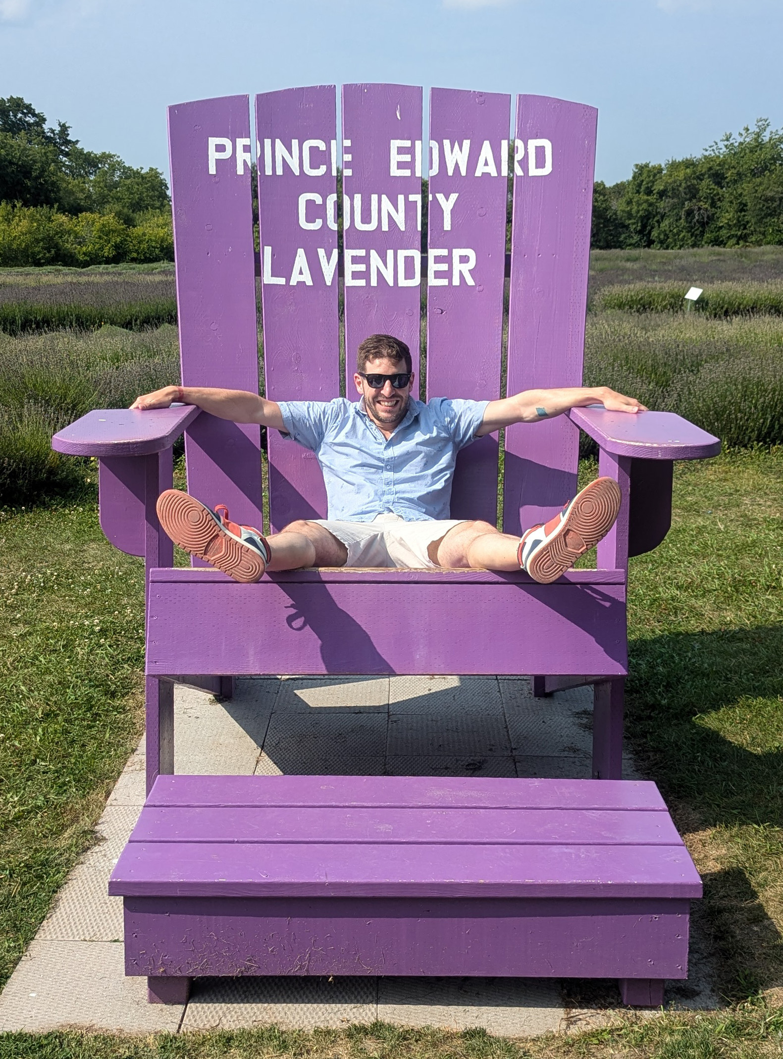 Phil sitting in a giant lavender-coloured Adirondack chair