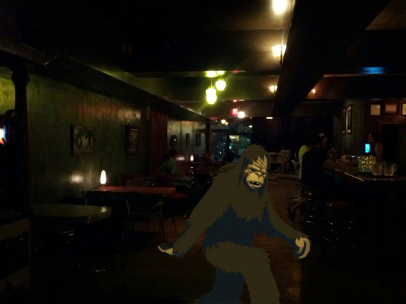 A DoodleCam photo of a sasquatch in a dark, mostly empty bar