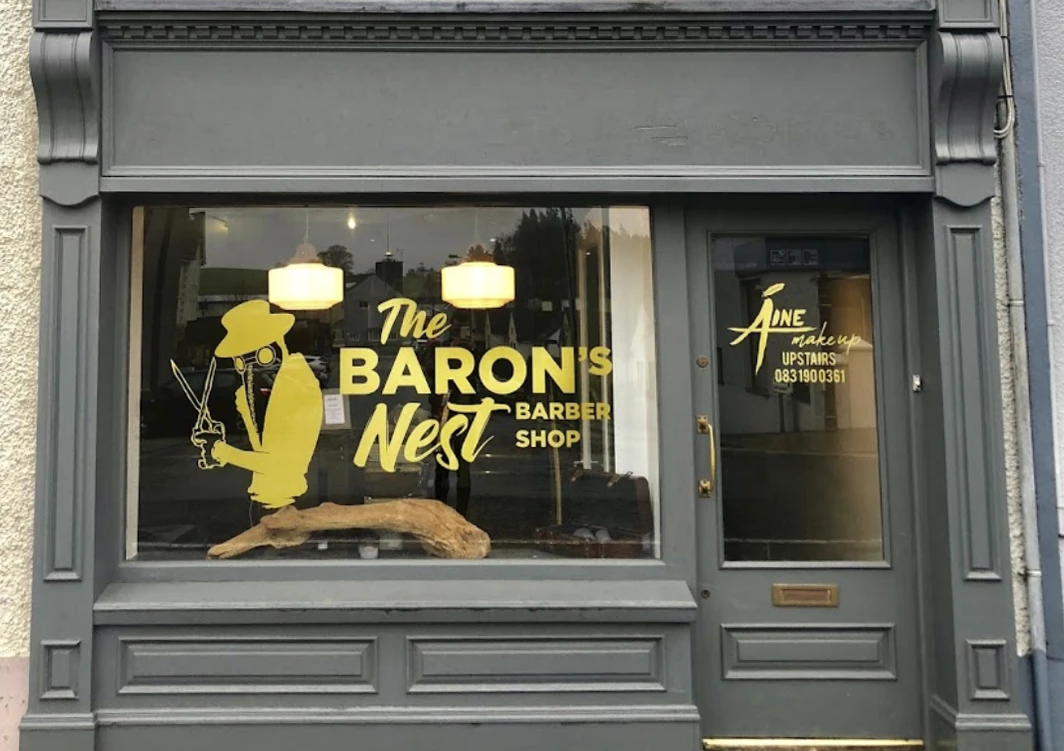 A photo of the Baron's Nest's storefront with the logo taking up most of the window